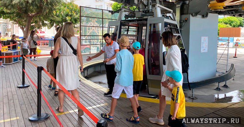 Работник приглашает посетителей фуникулера в кабинку